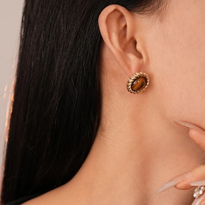 Gros plan de boucles d'oreilles rondes rétro avec pierre œil de tigre et bord doré