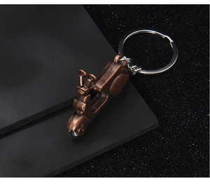 Detailed view of a vintage bronze motor scooter keychain on a black leather surface