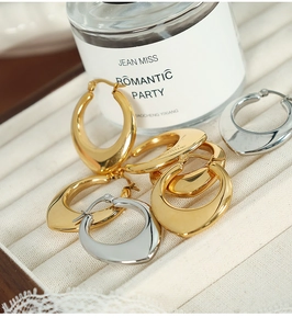 Macro detail of chunky gold and silver U-shaped hoop earrings on a jewelry tray
