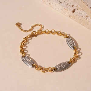 Dettaglio macro del bracciale dorato con ovali tempestati di cristalli e chiusura a moschettone