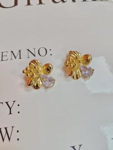 Detailed macro view of gold-plated flower stud earrings with clear teardrop zircon stones