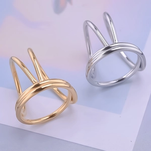 Dettaglio macro di anelli geometrici in acciaio inox oro e argento con design a orecchie di coniglio