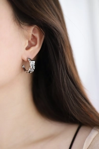 Silver wasteland style earrings featuring unique crumpled paper texture worn on model