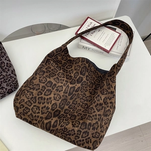 Flat lay of a large leopard print tote bag on a white surface with lifestyle props
