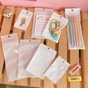 White pearlescent self-sealing bags for jewelry and stationery storage on a wooden tray