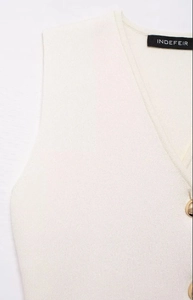Détail d'un gilet en tricot crème avec col en V, texture côtelée et boutons dorés