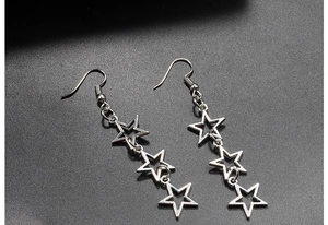 Detail shot of hollow star drop earrings featuring three connected stars in polished silver