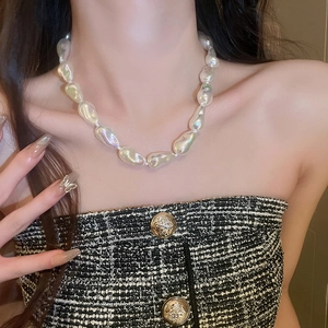 Macro view of baroque irregular pearl necklace on model neck with tweed clothing