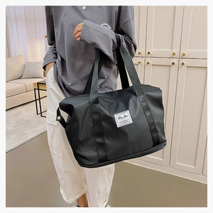 Detailed view of black nylon fitness bag featuring expandable bottom and woven logo