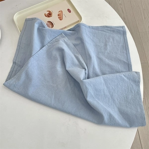 Detail of light blue linen-textured placemat with soft fabric weave on white table