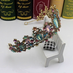Close-up of vintage gold bridal crown with colorful crystals on a decorative white bench