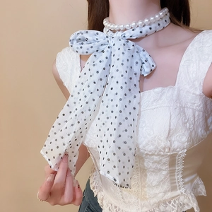 Detail of elegant polka dot silk scarf tied as a bow with double layer pearl necklace