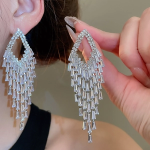 Close-up of silver tassel earrings with geometric diamond-cut crystals and long fringe