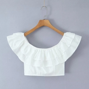 Detail of a white off-shoulder crop top with ruffled edges on a wooden hanger