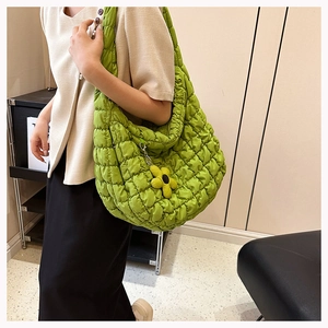 Detail of green quilted bubble tote bag with a yellow flower charm on a model