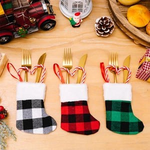 Three plaid Christmas stocking cutlery holders set on a warm festive wooden table