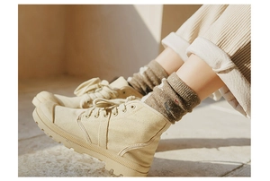 Close-up of beige canvas boots with thick rubber soles and stylish brown knitted socks