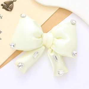 Close-up of elegant light yellow satin bow with sparkling rhinestones for accessories