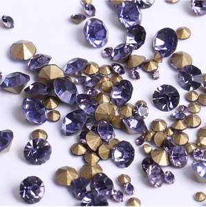 Macro shot of purple faceted glass rhinestones mixed with bronze cone metal nail art studs