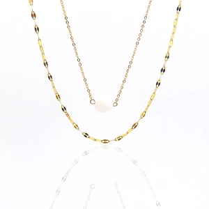 Detail of layered gold titanium necklace with a white gemstone and textured ripple chains