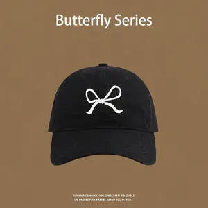 Detail shot of black sun protection cap featuring a white bow embroidery on canvas