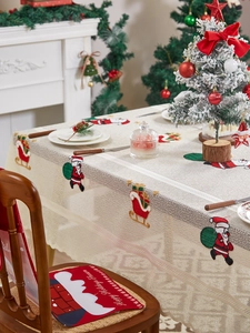 Detail showing Santa Claus embroidery on beige woven tablecloth with festive lace