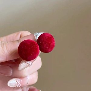 Gros plan de boucles d'oreilles en velours rouge portées pour montrer la taille