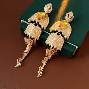 Macro detail of long gold-tone tassel earrings with white pearls and yellow teardrop gems