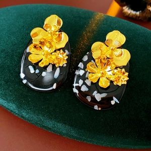 Detailed shot of vintage gold flower earrings with black resin and shell inlay