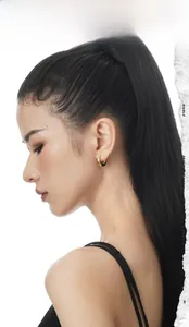 Close-up of chunky gold hoop earrings on a model showing high-polished metallic finish