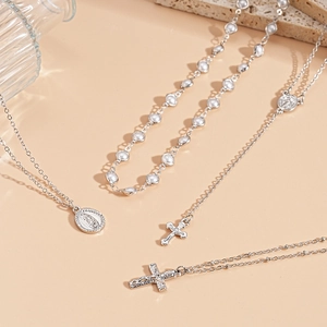 Detail view of silver layered necklace set with cross and oval saint portrait pendants