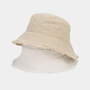 Close-up of fringe brim detail on stacked beige and khaki cotton bucket hats