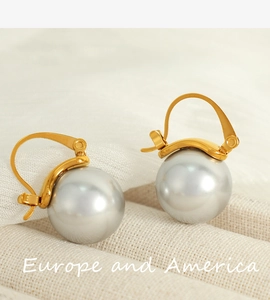 Détail de boucles d'oreilles dorées avec grandes perles grises et lustre satiné chic