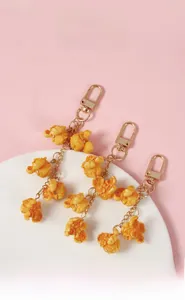 Macro shot of realistic PVC popcorn pendants with gold metal keychain clips on a plate