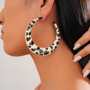 Close-up of model wearing large cow print C-shaped resin hoop earrings in black and white