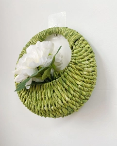 Macro detail of hand-woven corn rope wall basket with a decorative white faux flower