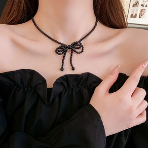Detail shot of a black beaded bow choker necklace worn on a model's neck