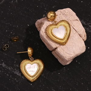 Détail des boucles d'oreilles cœur plaquées or 18 carats avec nacre et texture rayonnante