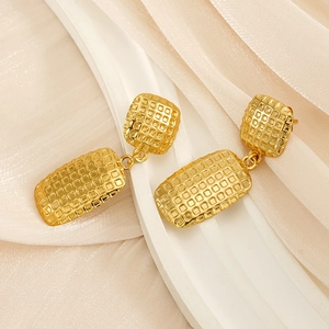 Detail shot of golden rectangular drop earrings with textured woven grid engraving