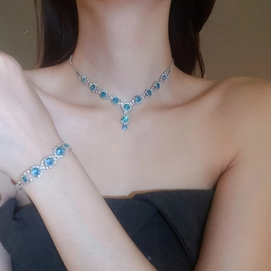 Detailed view of silver necklace and bracelet set with blue crystals on model
