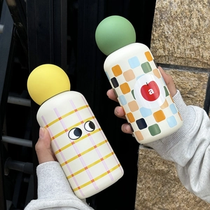 Close-up of portable 350ml stainless steel bottles with cute eye and pixel apple designs