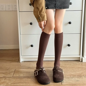 Close-up of dark brown knit calf socks paired with matching buckle suede mule shoes