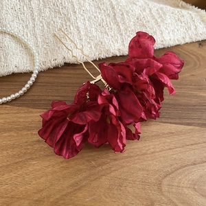 Close-up of three wine red fabric flowers on a gold U-shaped metal hairpin for women