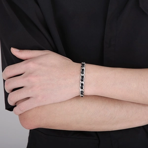Gros plan sur un bracelet en cuir noir tressé avec des chaînes cubaines en acier argenté