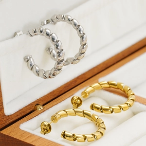 Minimalist twisted hoop earrings in 18k gold and silver finish on a display box