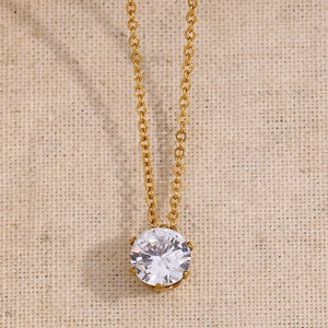 Collier élégant en or avec pendentif couronne en zircon blanc sur fond de lin beige naturel