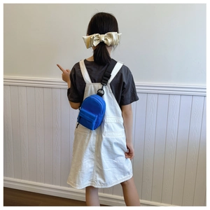 Rear view of a bright blue mini nylon crossbody bag worn over a casual black outfit