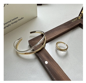 Detail of interlocking gold and silver wavy bangle and ring with polished finish