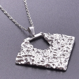 Detail of silver stainless steel necklace with textured irregular square pendant