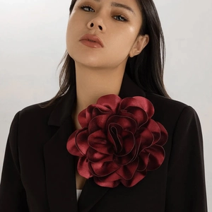 Deep red satin rose brooch featured on a black blazer for a retro fashion look